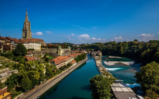 A pristine view of Bern Switzerland with a river running through the historic cityscape and blue sky above