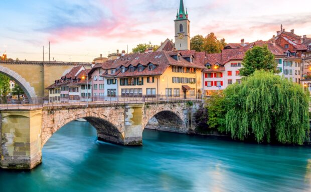 Beautiful historic bridge and colorful buildings in Bern Switzerland Wallpaper at sunset
