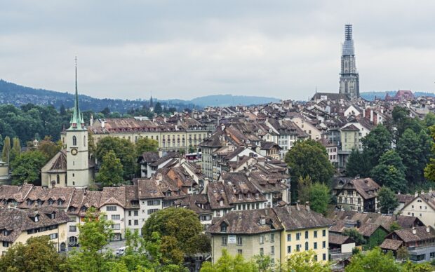 Bern Switzerland Wallpaper 2K Desktop A panoramic view of Bern Switzerland cityscape with historic buildings and church towers under an overcast sky