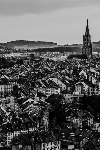 A black and white view of Bern Switzerland with old buildings and a tall church tower in the background