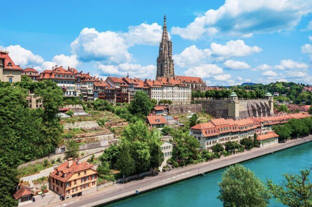 Bern cityscape with historic buildings and turquoise river under blue sky in Switzerland