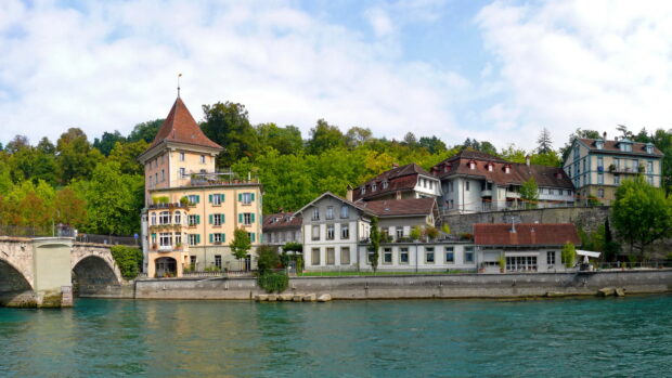 Historic buildings along the river in Bern Switzerland with lush green trees in the background