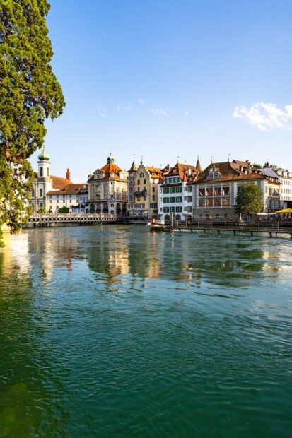 Bern Switzerland cityscape with historic buildings reflecting on the Aare River under a clear blue sky