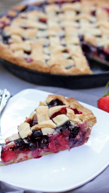 A slice of berry pie with a lattice crust on a white plate next to the whole pie, 4K Mobile Wallpaper