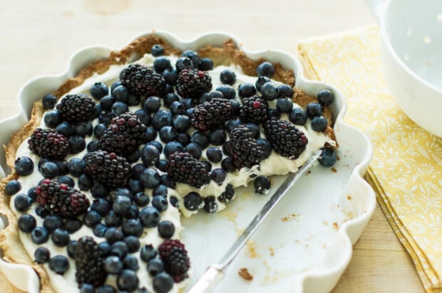 A berry pie topped with cream and fresh blueberries sitting on a wooden table, 2K Desktop Wallpaper