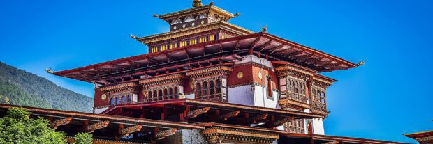 Traditional Bhutan architecture surrounded by green hills under a clear blue sky