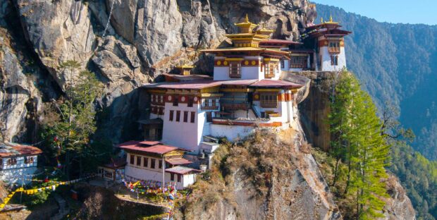 Traditional Bhutan architecture built on a rocky cliff surrounded by forest and mountains