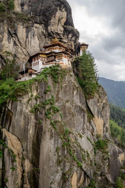 Ancient Bhutan cliff monastery nestled among lush green trees and rocky mountains