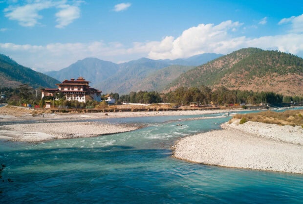 Traditional Bhutan architecture along a river surrounded by mountains in Bhutan