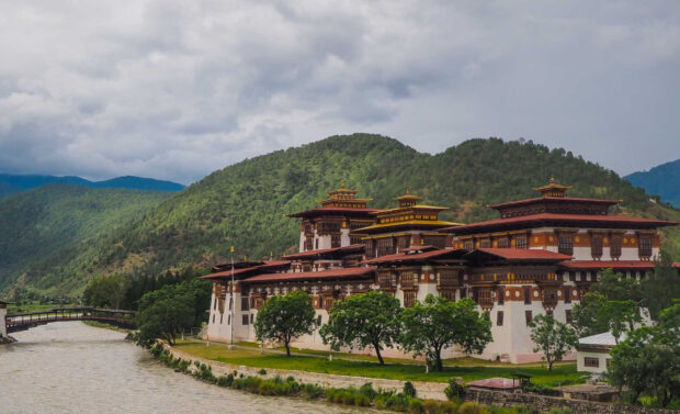Traditional Bhutan architecture with green hills and river surrounding the structure