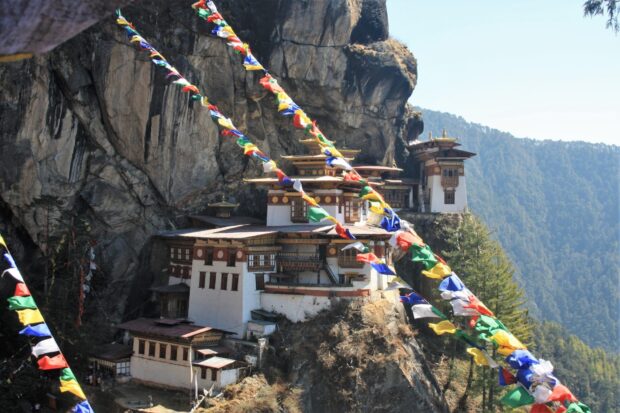 Traditional Bhutanese monastery built on a cliff surrounded by colorful prayer flags