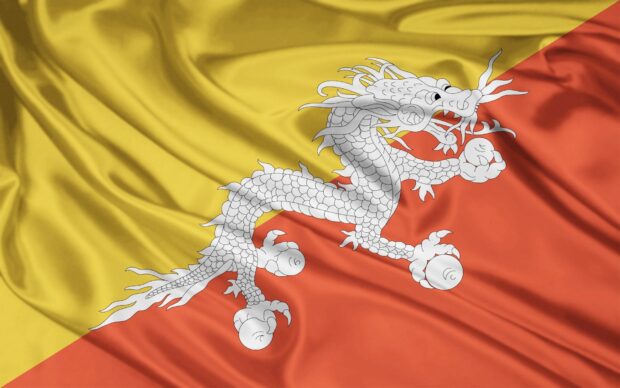 White dragon on the yellow and orange flag of Bhutan with fabric texture