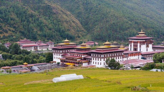 Traditional Bhutan architecture surrounded by green hills and fields in Bhutan