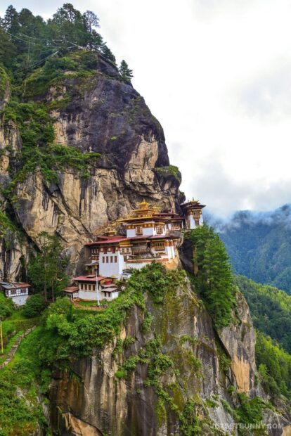A scenic view of Bhutan monastery perched on a cliff surrounded by green forest