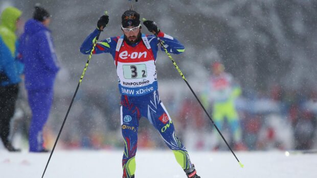 Male biathlon athlete skiing in snowy winter conditions during a competition in Ruhpolding