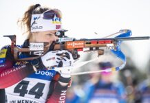 Female biathlon athlete aiming with rifle during competition
