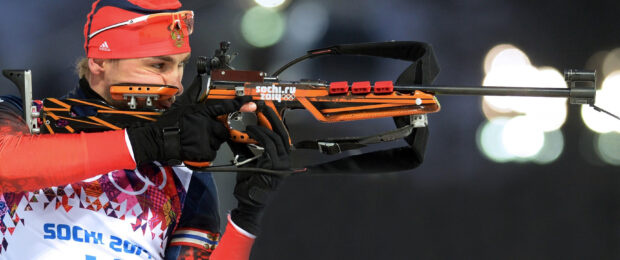 A biathlon athlete aiming with a rifle during a competition in Sochi 2014