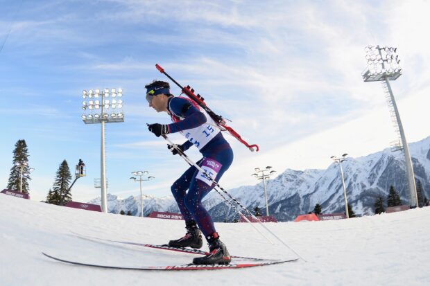 A biathlon athlete skiing on snow during a winter competition in the mountains