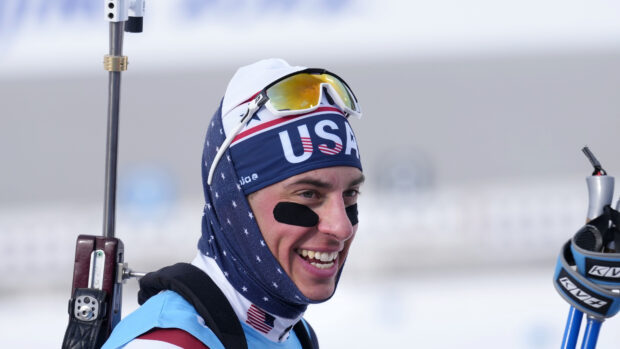 Biathlete wearing USA headgear smiling during winter competition
