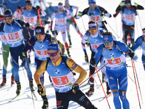 Biathlon athletes competing in a race with ski poles on a snowy track