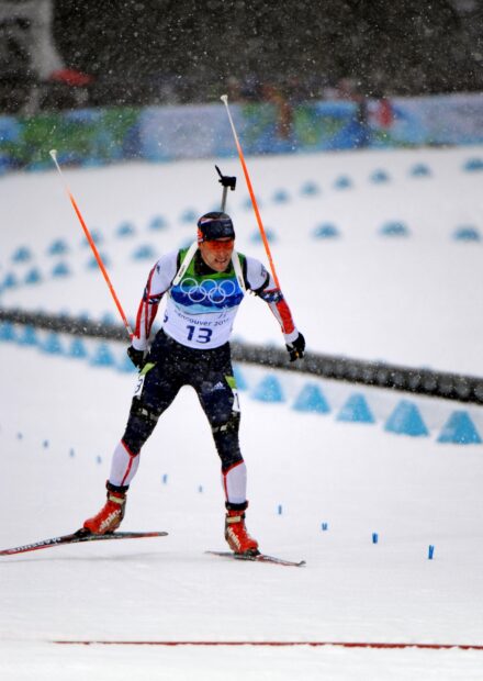 A biathlon athlete skiing with poles on a snowy course during a race