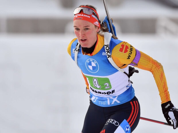 Female biathlon athlete skiing intensely during a competition in cold weather