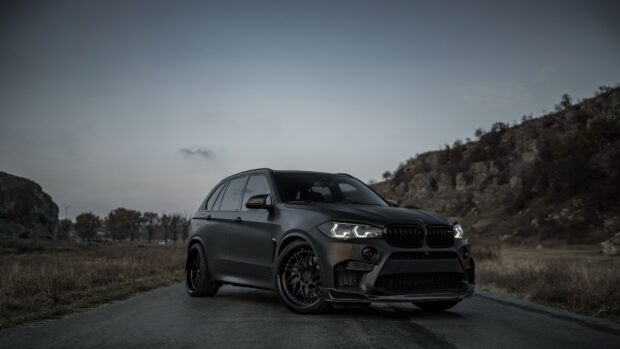 A black BMW X5 is parked on a road with hills in the background, 4K Desktop Wallpaper