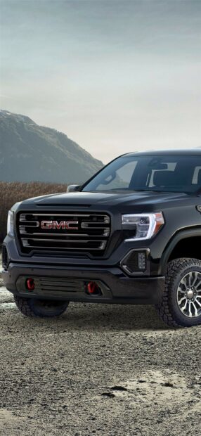 A black GMC truck stands on a rocky surface with mountains in the background, HD Phone Wallpaper