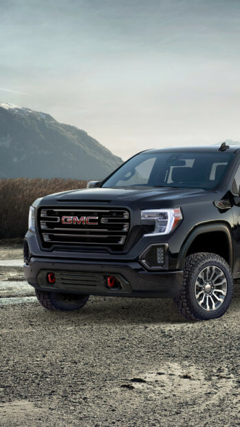 A black GMC truck is shown parked on a rocky surface with mountains in the background, 2K Phone Wallpaper