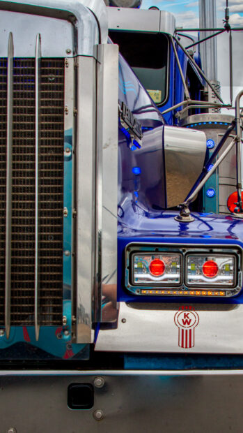 This image shows the front view of a blue Kenworth truck with detailed headlights and logo, 4K Mobile Wallpaper