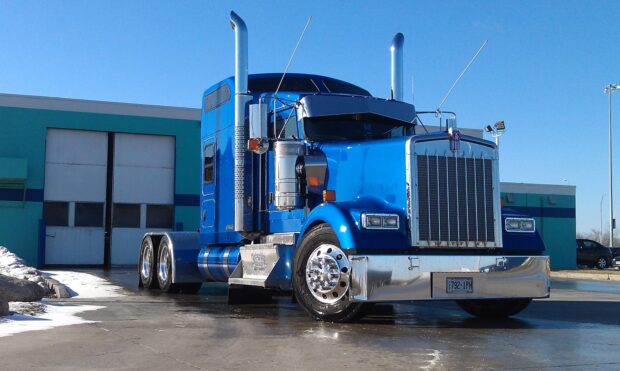A blue Kenworth truck is parked outside a turquoise industrial building under a clear sky, HD Desktop Wallpaper