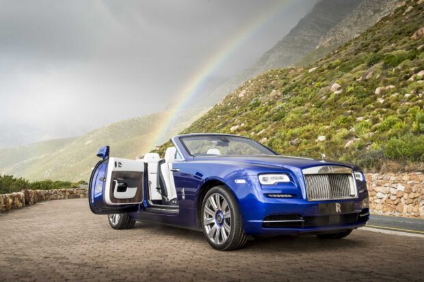 A blue Rolls Royce Dawn with its door open stands on a mountain road under a rainbow, HD Desktop Wallpaper