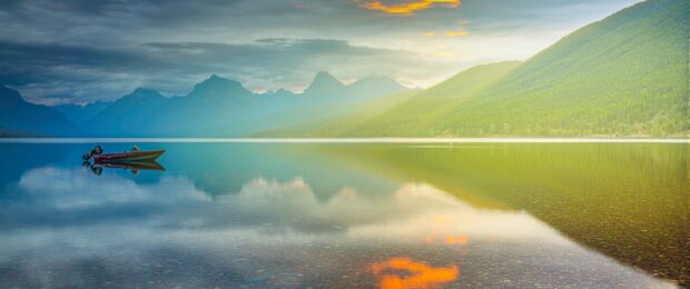 A red boat floats on a calm lake surrounded by mountains in Montana Wallpapers, 2K Desktop Wallpaper