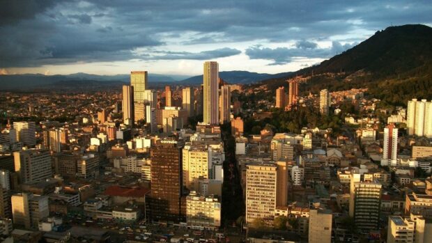 The Bogota city skyline shows tall buildings under a dramatic cloudy sky, HD Desktop Wallpaper