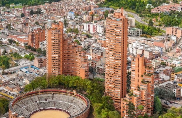 The Bogota cityscape features tall orange buildings and a historic bullring surrounded by greenery, HD Desktop Wallpaper