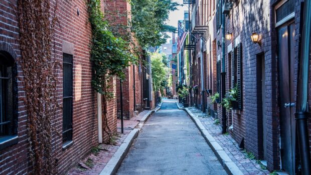 Narrow Boston alleyway with brick buildings and American flags lining the street