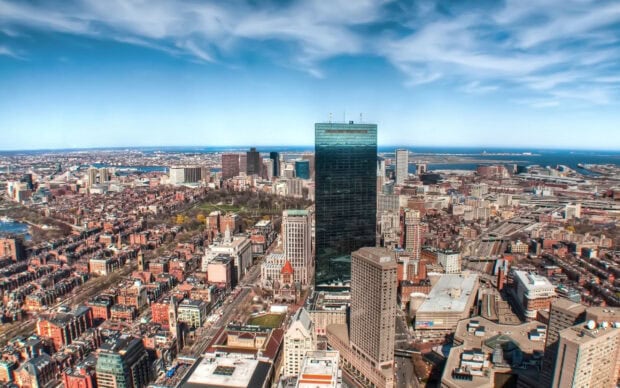 Aerial view of Boston cityscape with iconic skyscrapers and waterfront under a clear blue sky