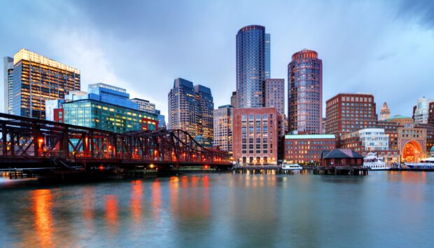 Boston city skyline featuring illuminated skyscrapers and waterfront reflections at dusk