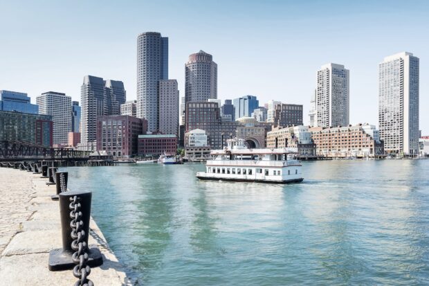 A boat sailing on the harbor with Boston skyline in the background