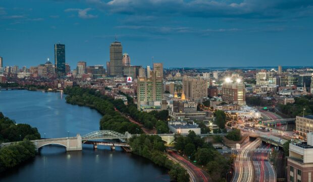 A high quality Boston skyline featuring the cityscape along the river at dusk with clear skies