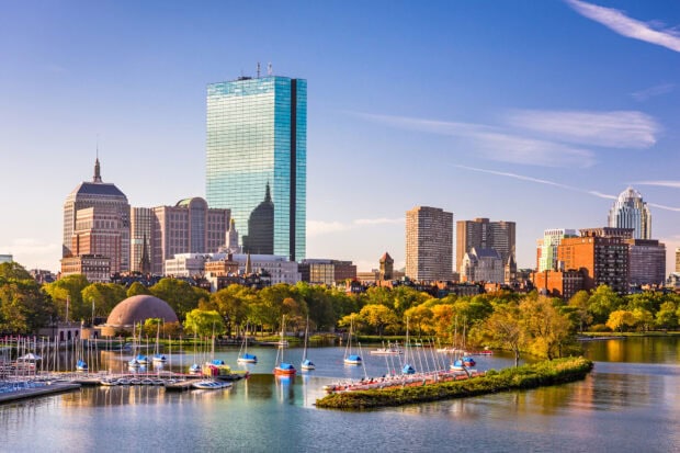 Boston city skyline with sailboats on the water and clear blue sky in autumn