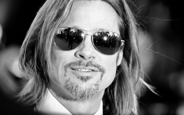 Close up of Brad Pitt wearing sunglasses and smiling at a public event