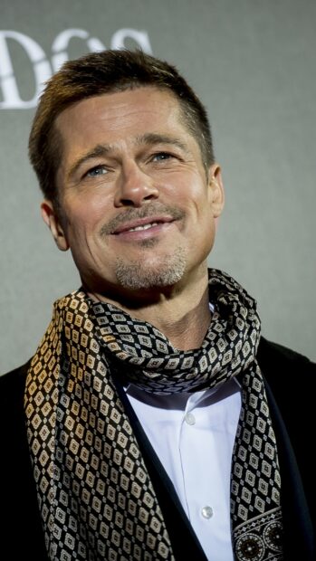 Brad Pitt wearing a stylish patterned scarf and white shirt with a confident smile
