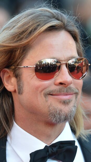 Brad Pitt with sunglasses smiling at the red carpet event