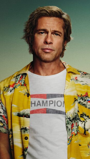 Brad Pitt wearing a yellow patterned shirt and white Champion t shirt with a serious expression