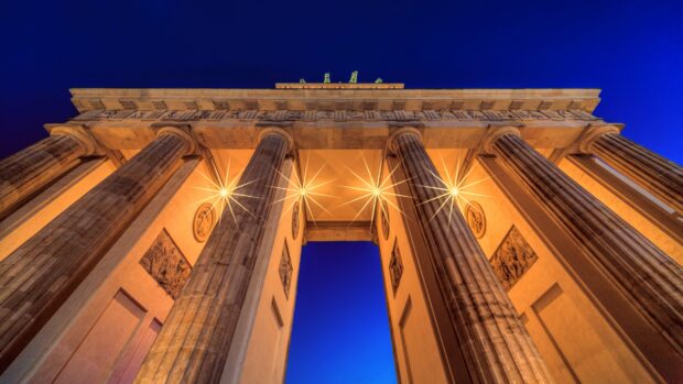 The Brandenburg Gate in Berlin glows warmly against a deep blue night sky, 4K Desktop Wallpaper