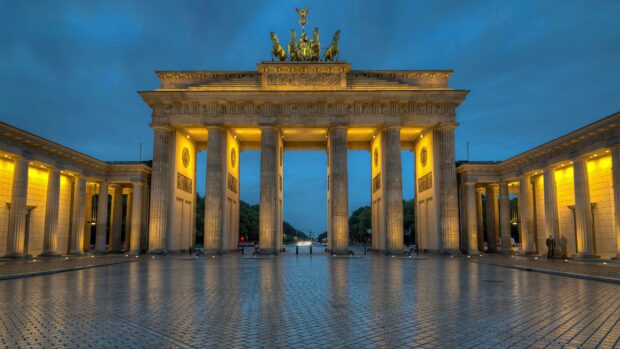 The Brandenburg Gate in Berlin is illuminated with yellow lights during the early evening, 4K Desktop Wallpaper