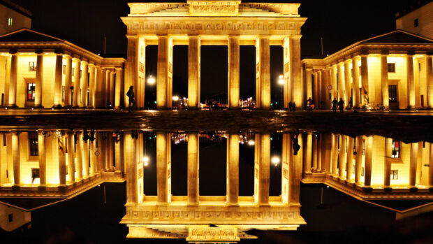 The Brandenburg Gate in Berlin is brightly lit with reflections on water at night, 4K Desktop Wallpaper