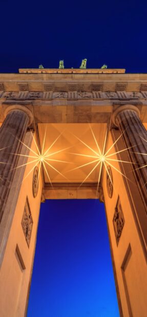 The Brandenburg Gate Berlin stands brightly lit against a deep blue sky, 2K Phone Wallpaper