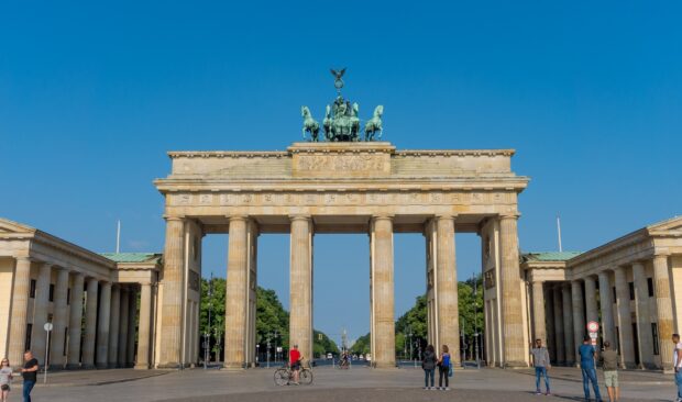 The Brandenburg Gate in Berlin stands under a clear blue sky with people walking nearby, HD Desktop Wallpaper